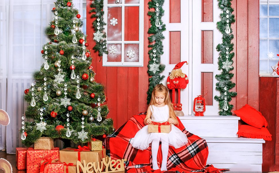 Girl opening gift beside Christmas tree with clear snowflake and icicle ornaments
