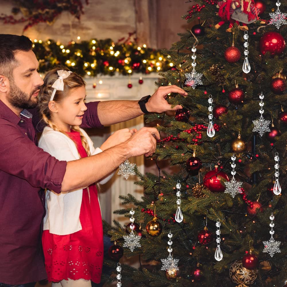 Father and daughter decorating a Christmas tree with clear snowflake and icicle ornaments