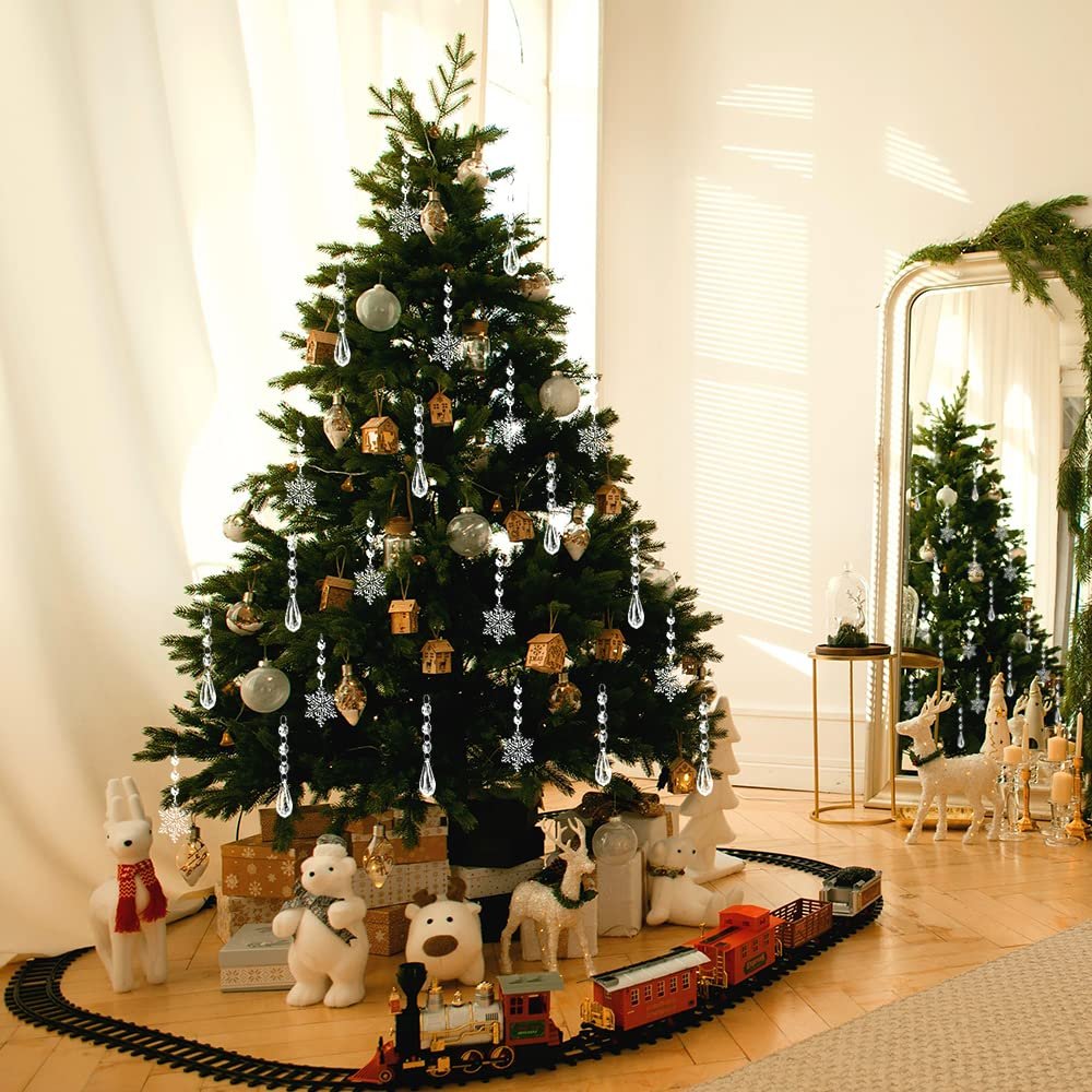 Christmas tree decorated with clear acrylic snowflake and icicle ornaments, surrounded by festive decor including stuffed animals and a toy train.