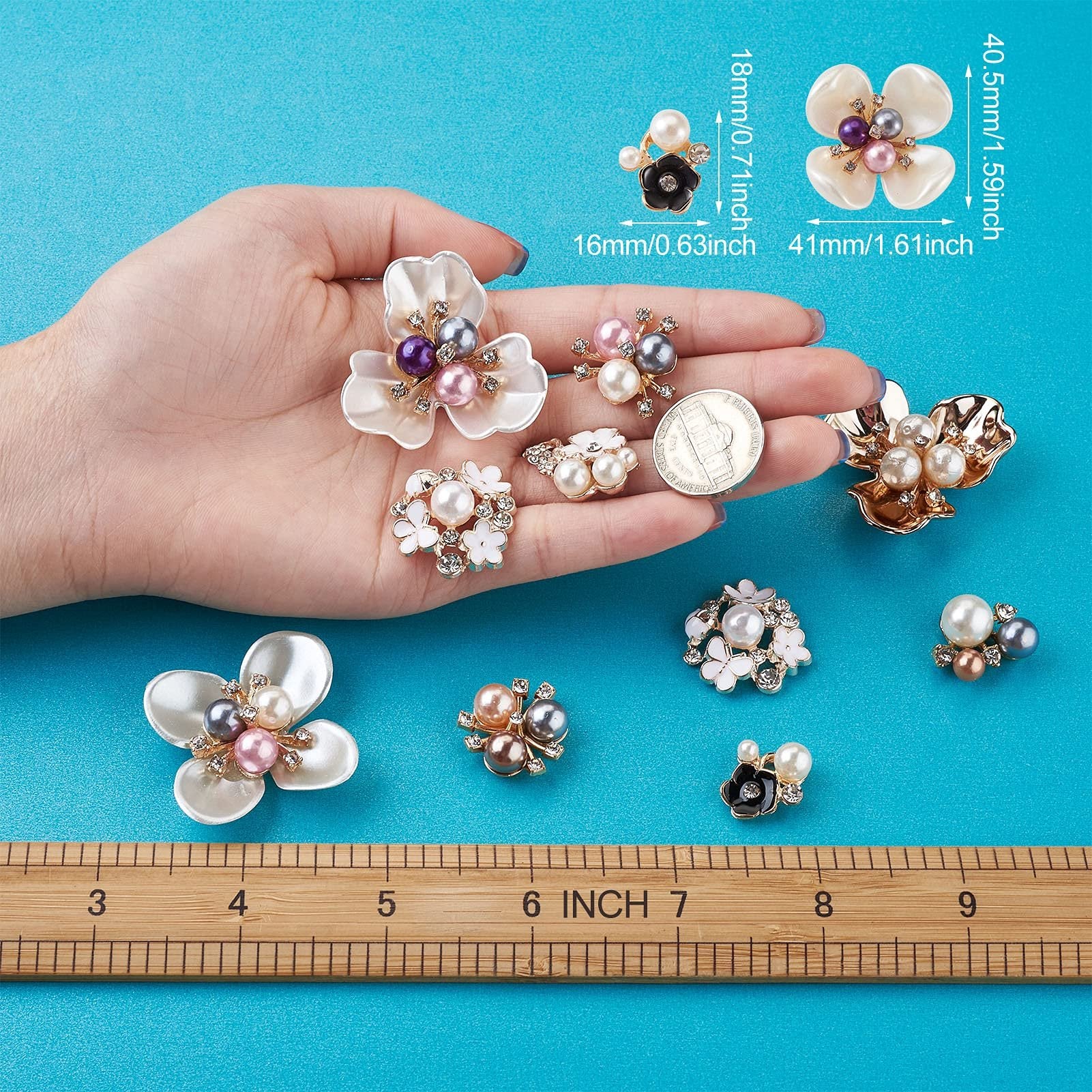 Hand holding various pearl and rhinestone flower flatback cabochons with ruler for scale. Mixed colors.