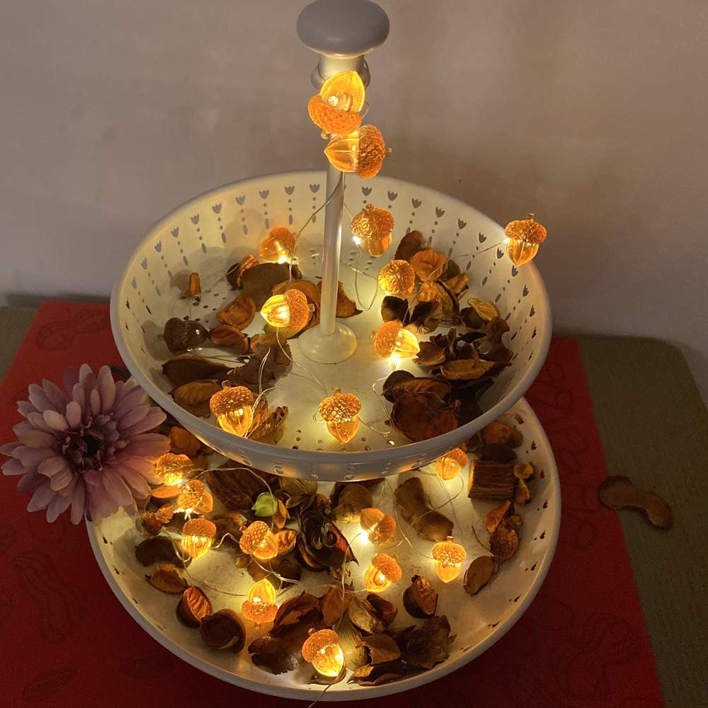 Acorn-shaped string lights with 30 LEDs on a two-tiered stand with dried leaves and a flower.