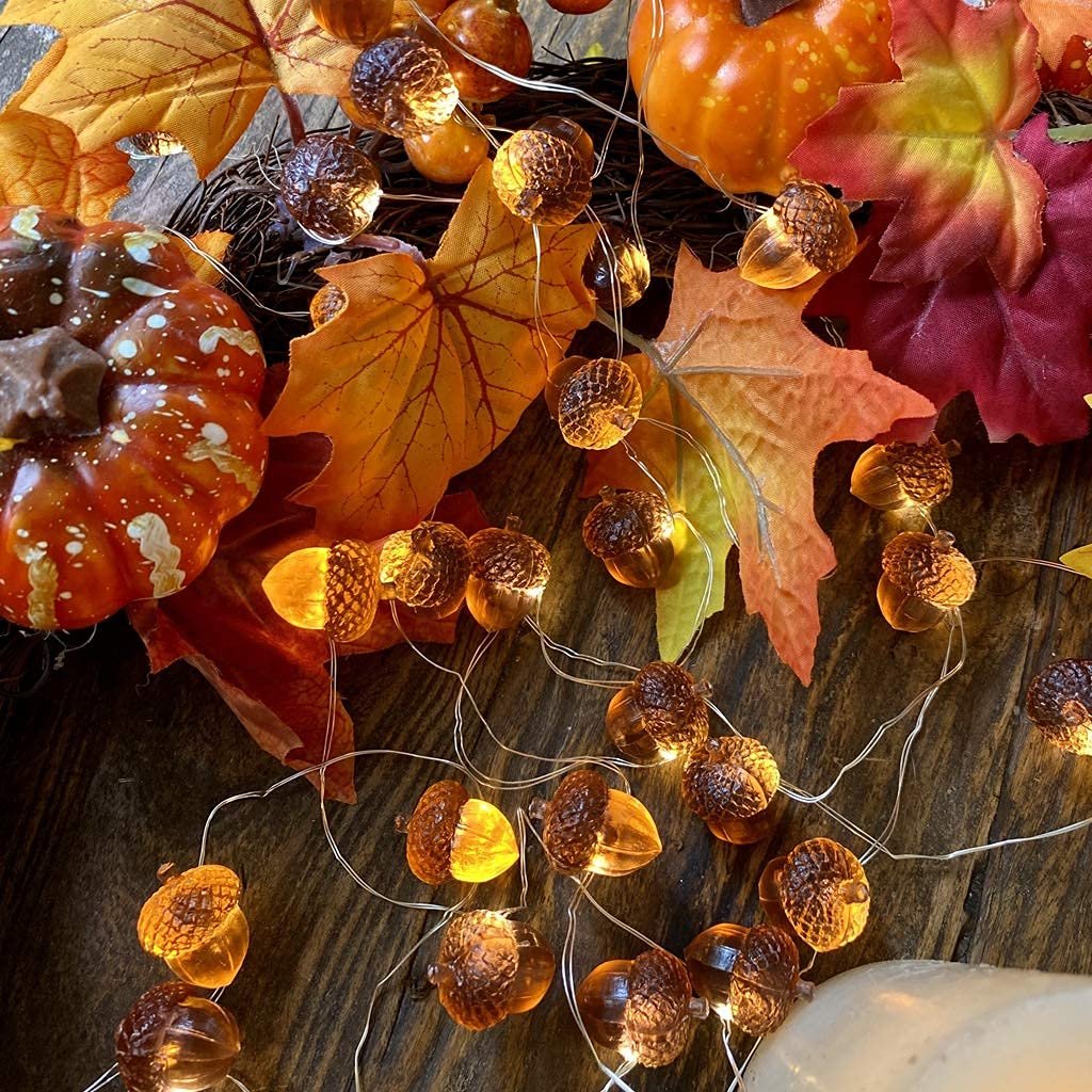 3D acorn string lights with pumpkins and fall leaves on a wooden surface