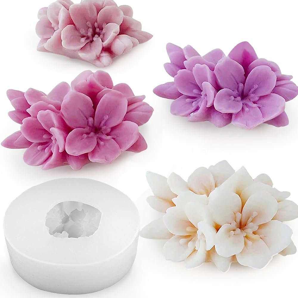 Silicone mold and three cherry blossom flower soaps in pink, purple, and white on a white background.