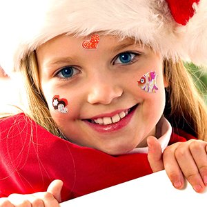 Young girl wearing a Santa hat and red shirt, smiling with puffy stickers on her face.