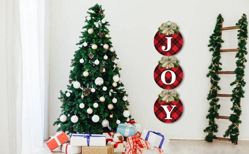 Three round buffalo plaid Christmas wreath signs spelling JOY, displayed next to a decorated Christmas tree and a garland-draped ladder.