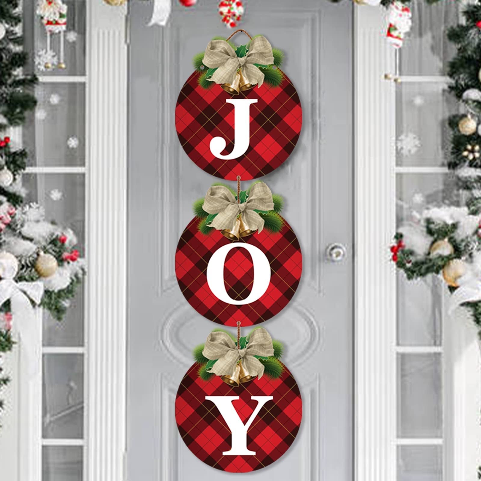 Three round buffalo plaid Christmas wreath signs spelling JOY, hanging on a door with festive decorations.