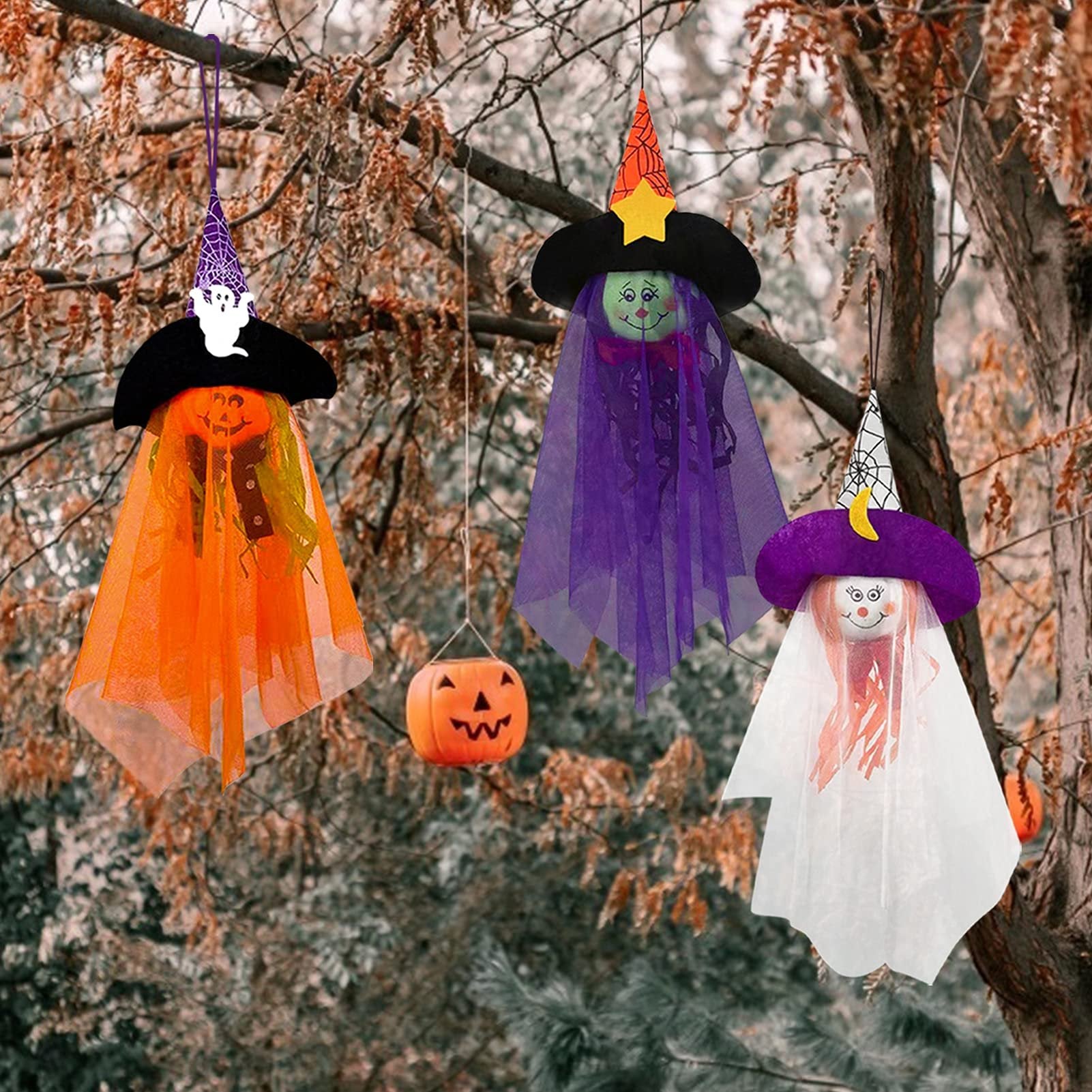 Three Halloween hanging ghost decorations with witch hats and pumpkin faces, suspended from tree branches.