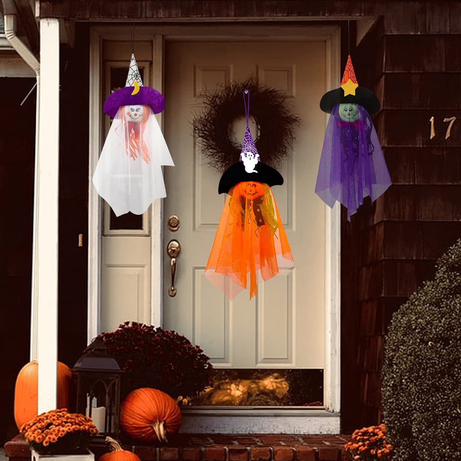 Three Halloween hanging ghost decorations with witch hats and tulle skirts displayed on a porch.