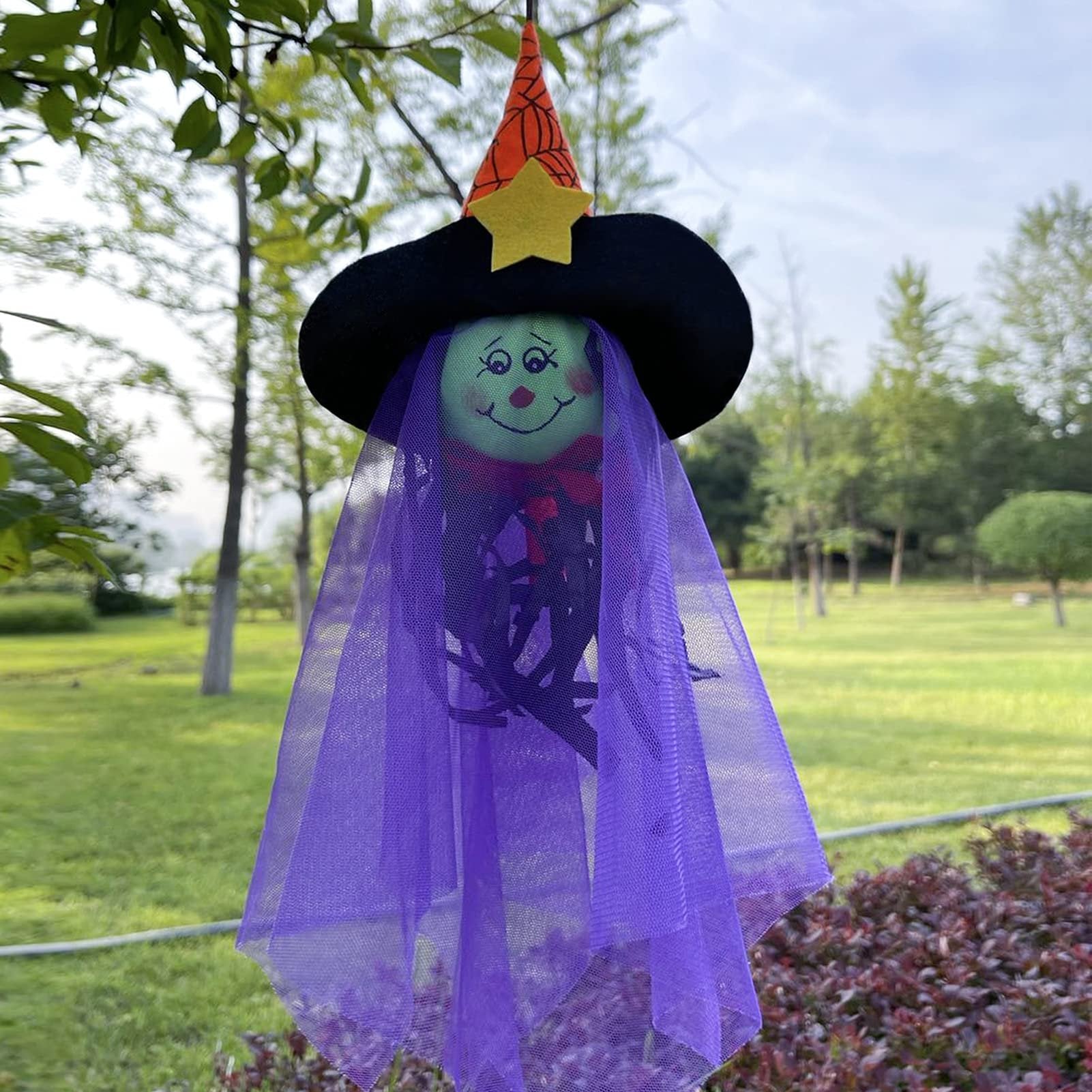 Halloween hanging ghost decoration with witch hat and purple veil, outdoors