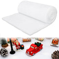 Rolled artificial snow blanket with Christmas village display including Santa, red truck, and pinecones