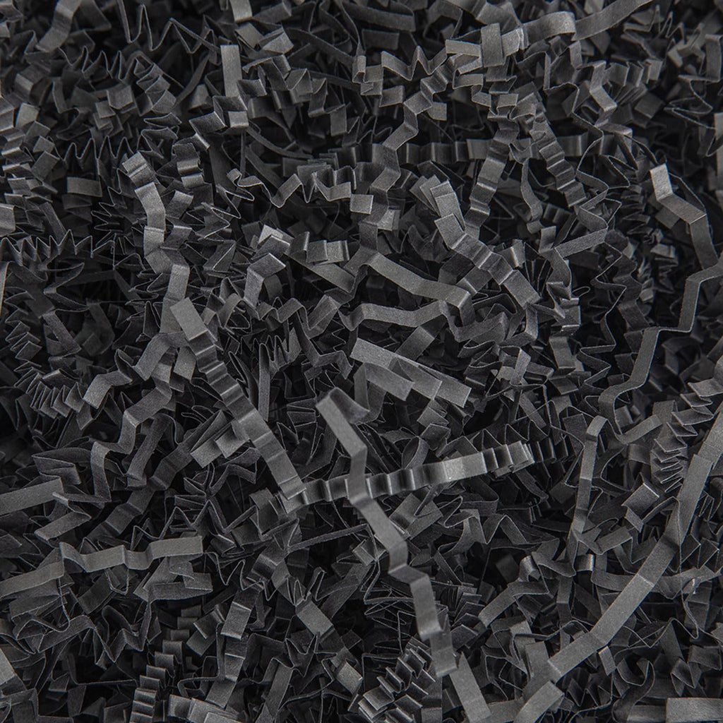 Close-up overhead view of black crinkle cut paper shred filler for gift baskets and packaging.