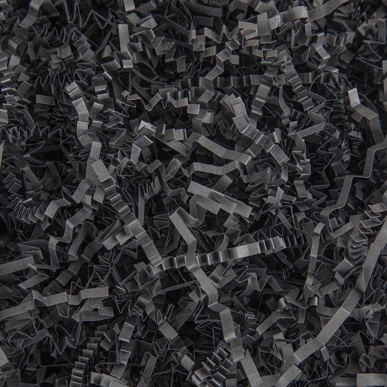 Close-up overhead view of black crinkle cut paper shred filler for gift baskets and packaging.