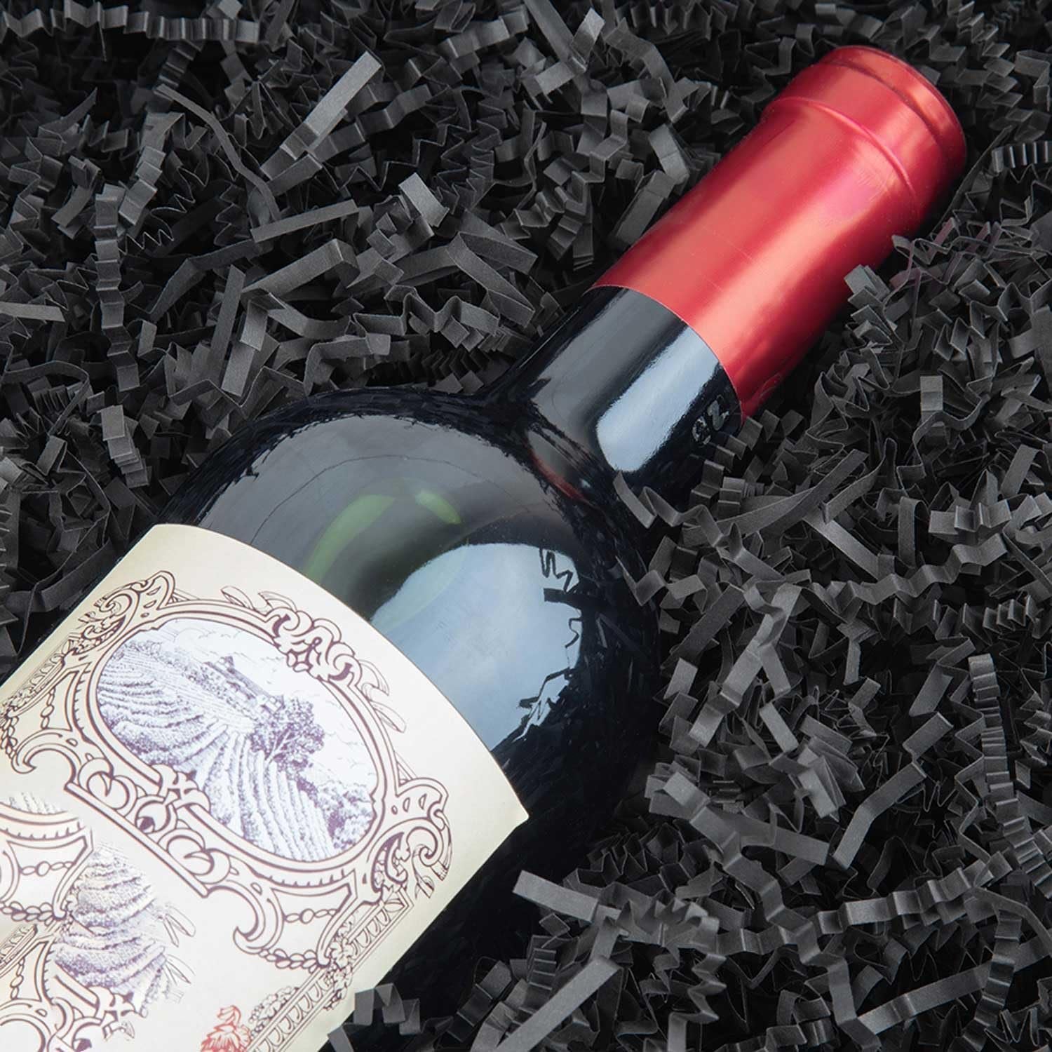 Black crinkle cut paper shred filler with a wine bottle lying on its side