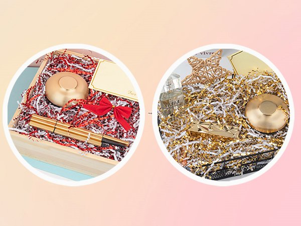 Gift basket filler with gold pen, red bow, and gift tag in wooden box; gold shredded paper with perfume bottle and star decoration in basket