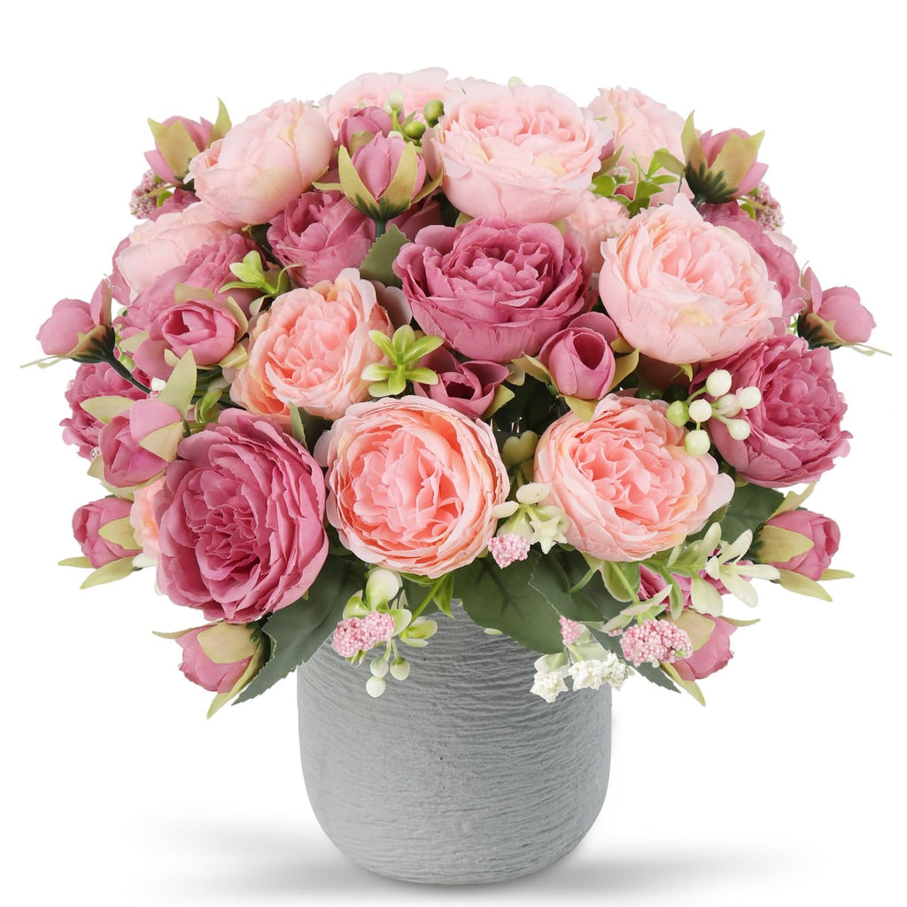 Pink and rose artificial peony bouquet with berries and green leaves in a gray textured vase, front view.