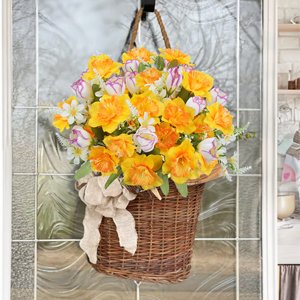 Wicker basket filled with artificial daffodils and tulips, hanging on a glass door with a burlap bow.