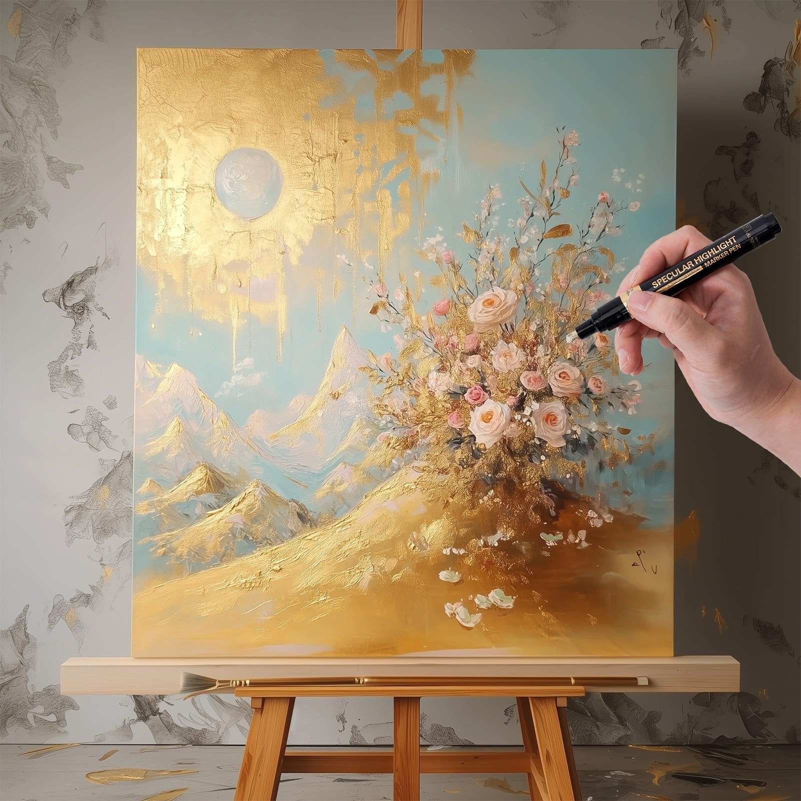 Hand holding a black marker pen with 'SPECULAR HIGHLIGHT MARKER PEN' text, applying it to a gold and pastel abstract painting on an easel.