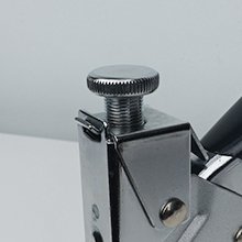 Close-up of the adjustment knob on a staple gun, showing metallic details and ribbed texture.
