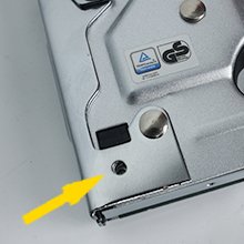 Close-up of a silver manual staple gun showing a yellow arrow pointing to a screw hole.