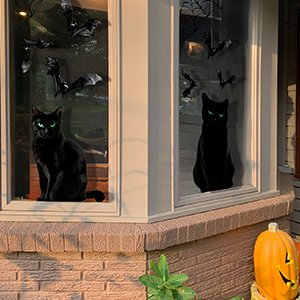 Two black cat Halloween window clings with bats and spiderwebs on a window.