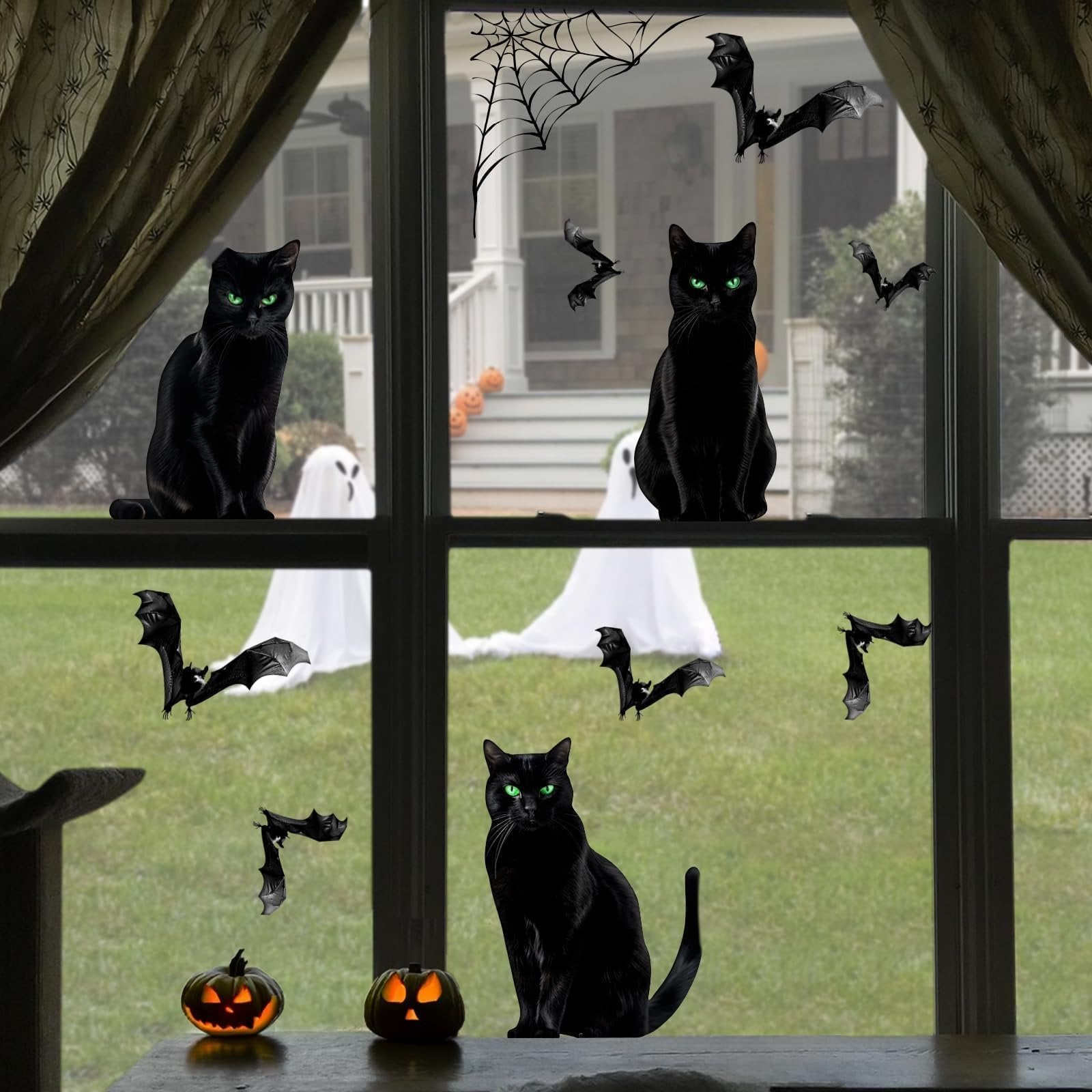 Black cat Halloween window clings with bats, spiderwebs, ghosts, and pumpkins on a window overlooking a yard.