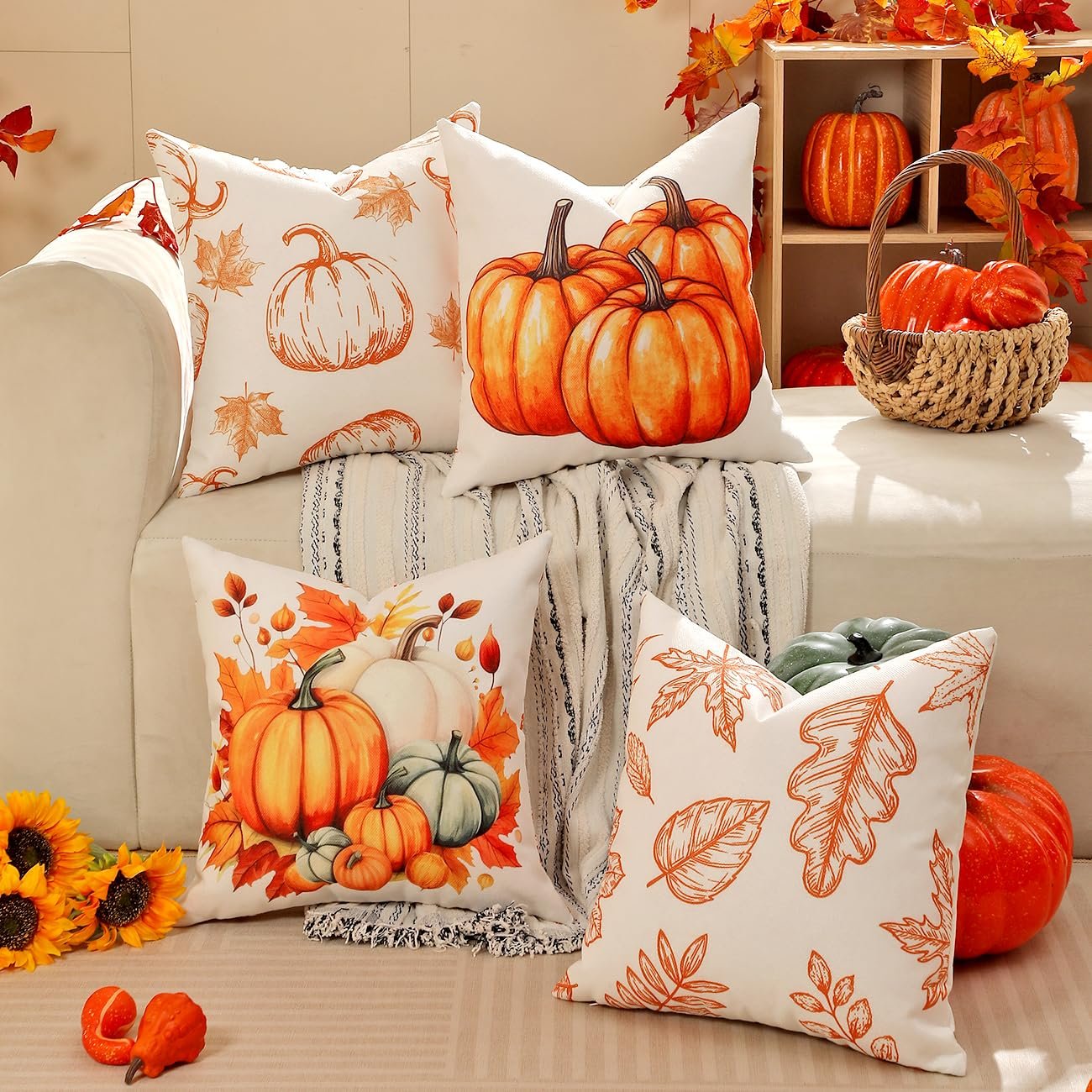 Four fall-themed throw pillow covers with pumpkin and leaf designs arranged on a couch.