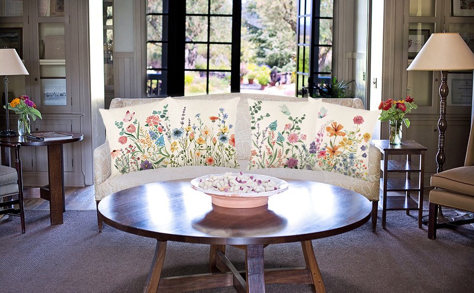 Four floral butterfly print pillow covers displayed on a sofa in a living room setting.