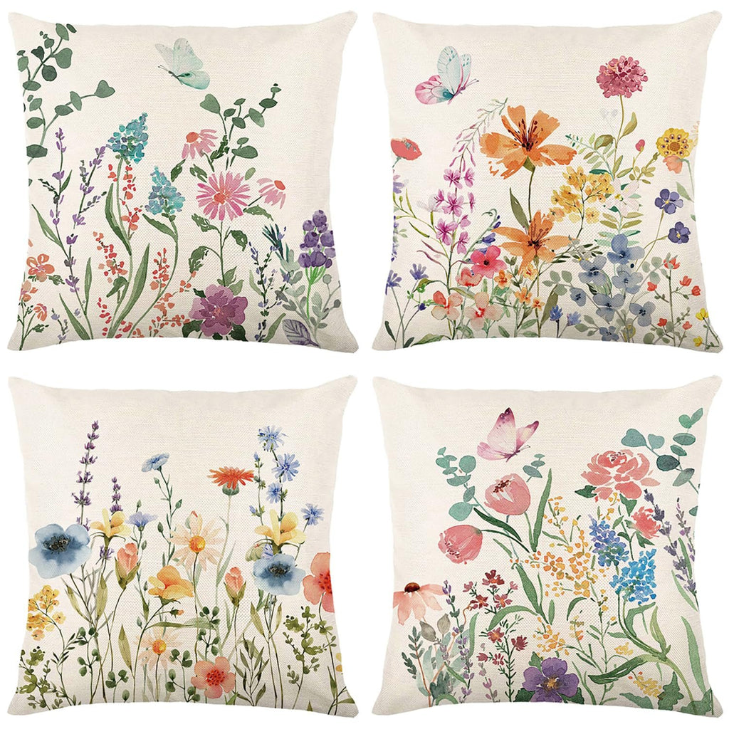 Four square pillow covers with watercolor floral and butterfly designs on a faux linen background.