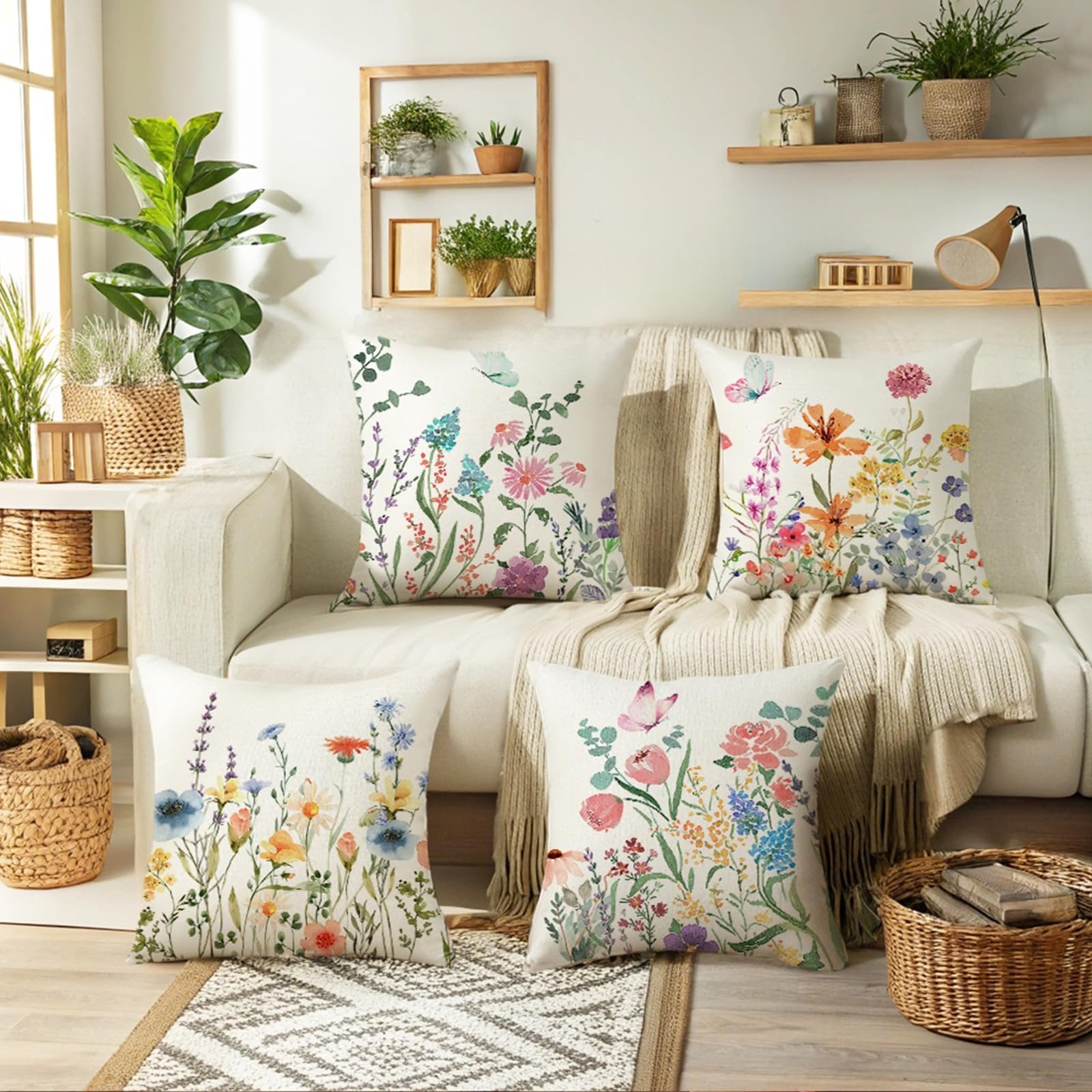 Four decorative throw pillow covers with floral and butterfly designs arranged on a sofa.