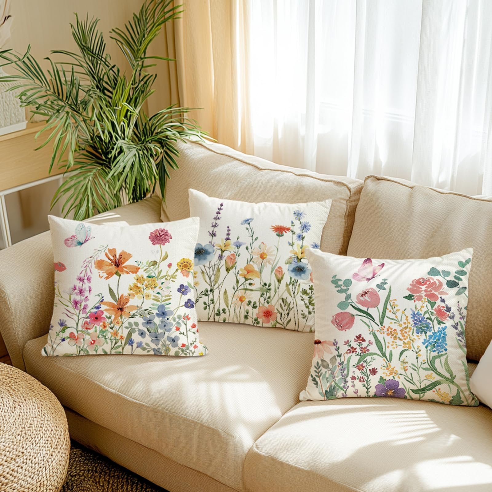 Three floral butterfly print pillow covers arranged on a beige sofa with a potted plant.