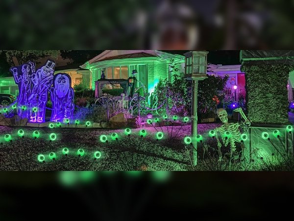 Halloween yard decorated with spooky figures and glowing green eyeball pathway lights at night