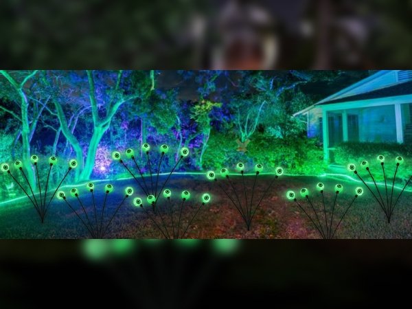 Four clusters of 24-LED solar eyeball pathway lights glowing green in a yard at night, illuminating trees and a house.