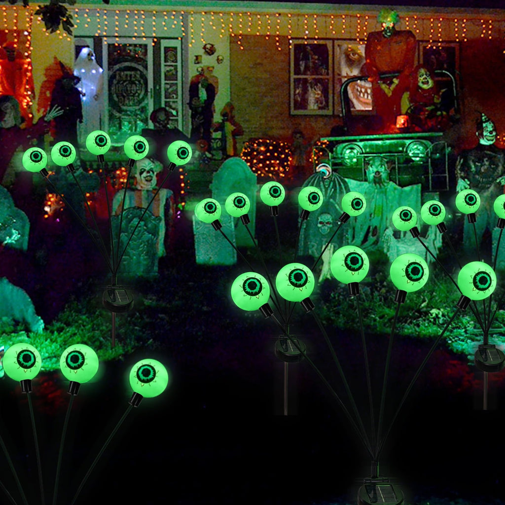 Halloween eyeball pathway lights glowing green in a yard with spooky decorations
