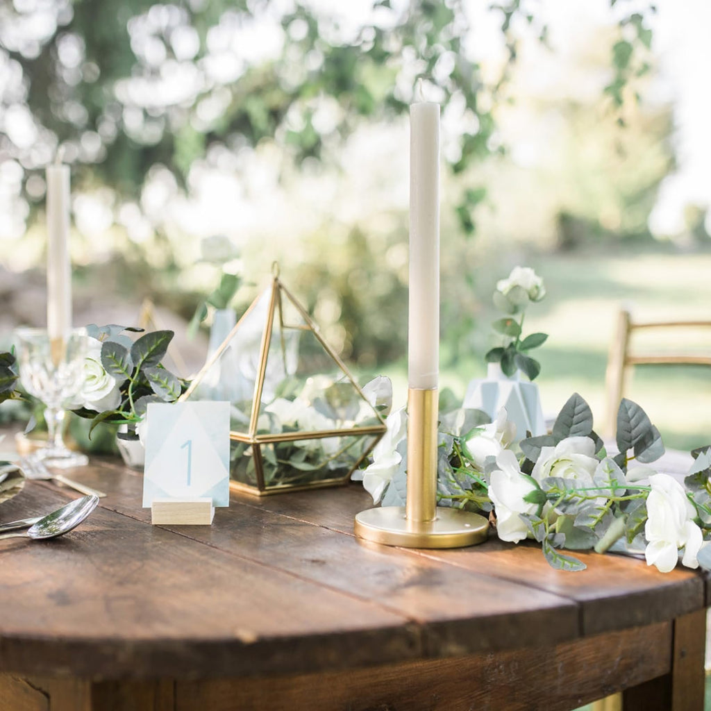 Table setting with artificial white rose garland, candle, and table number 1