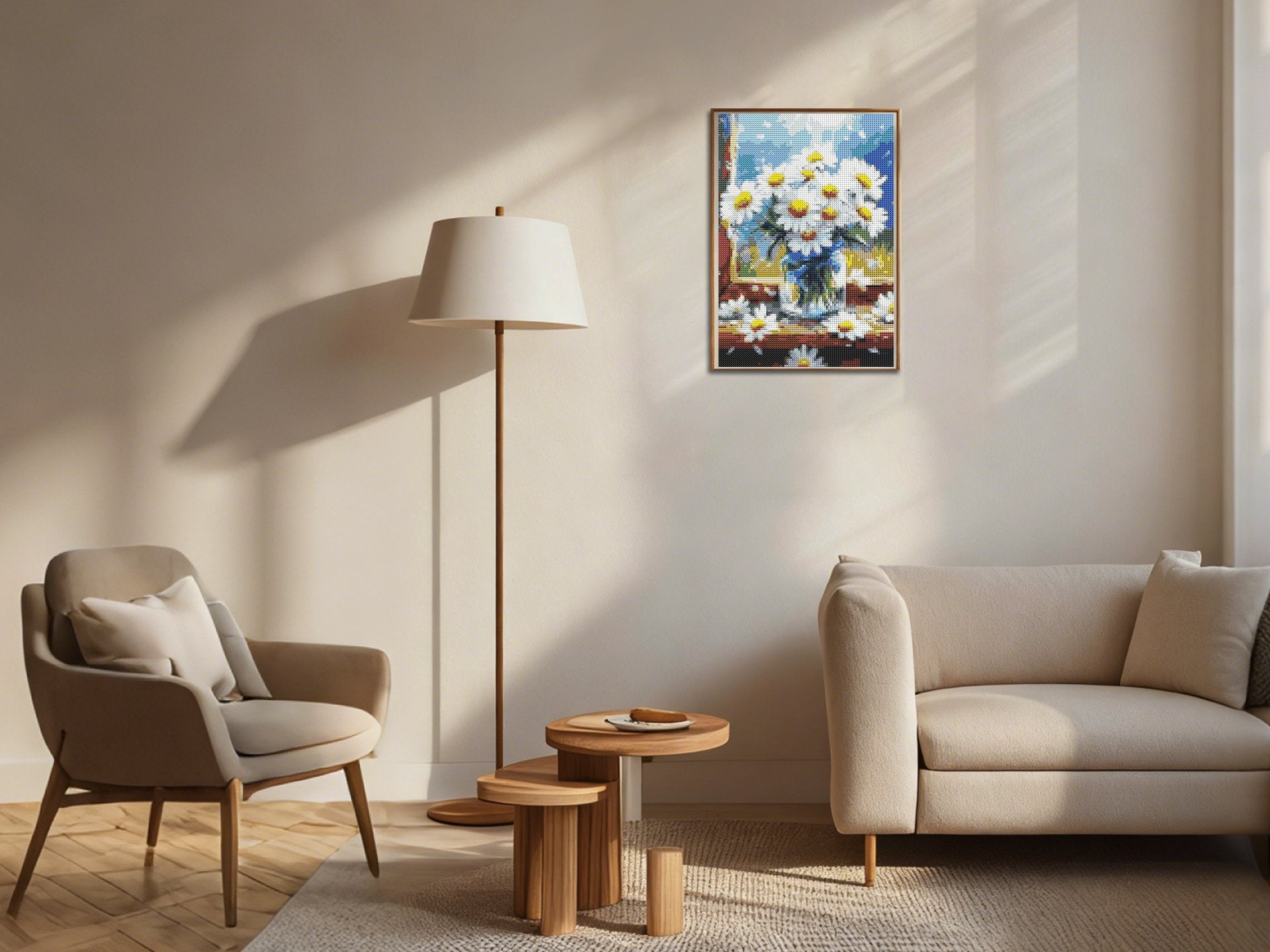 Framed diamond painting of daisies in a vase hanging on a wall in a living room setting with a sofa and chair.