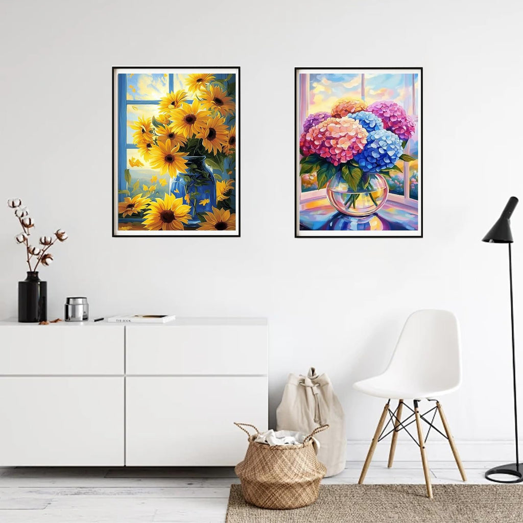 Two framed diamond paintings of floral arrangements on a wall, one with sunflowers, the other with hydrangeas.