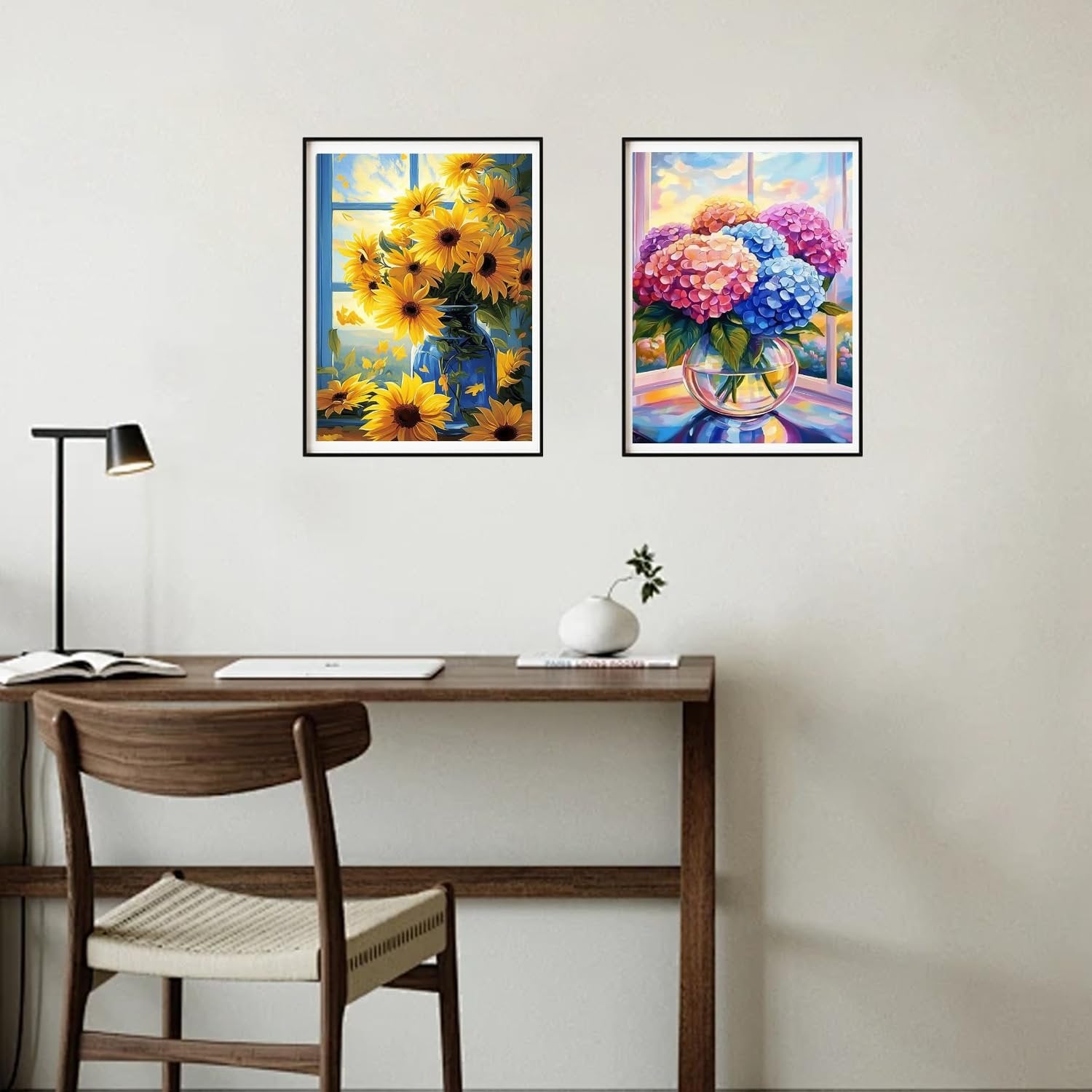 Two framed floral diamond paintings hanging on a wall above a wooden desk with a chair.