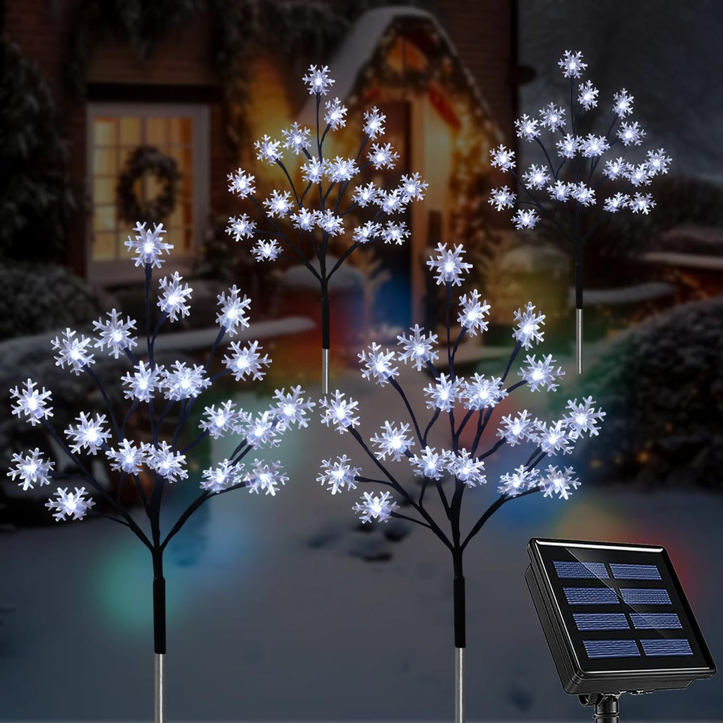 Three snowflake stake lights with a solar panel in a snowy yard at dusk