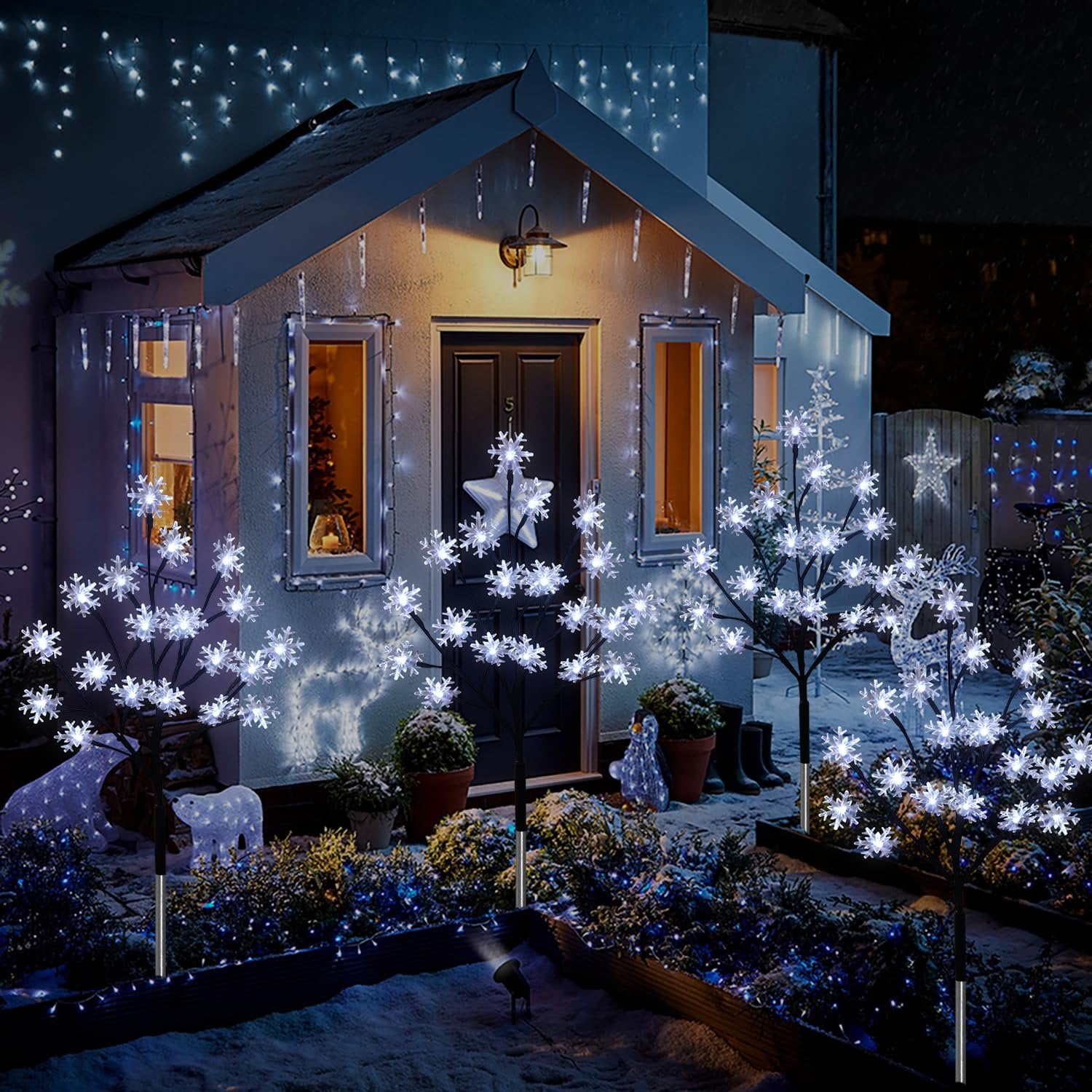 Outdoor Christmas snowflake stake lights decorating a house entrance at night with snow on the ground.