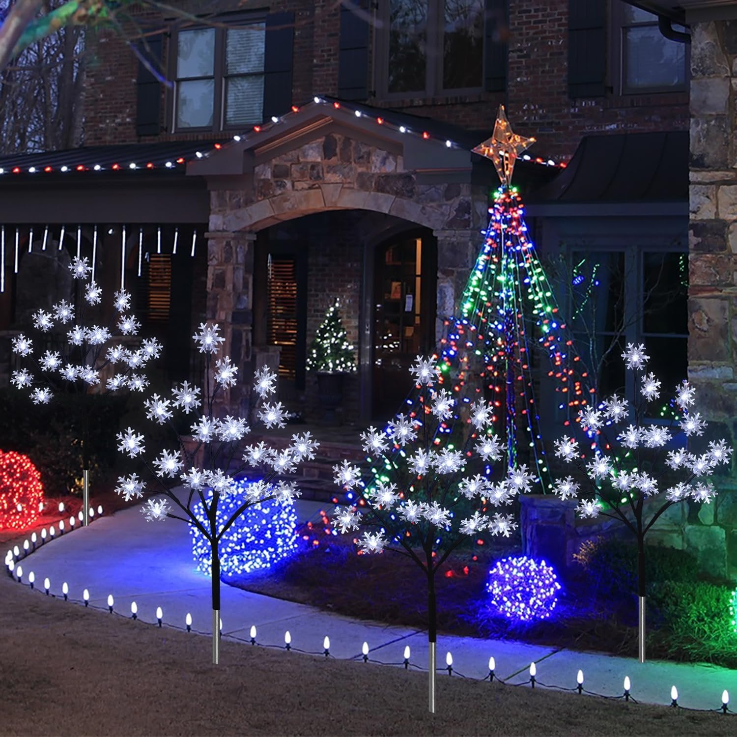 Outdoor Christmas snowflake stake lights and tree lights decorating a house entrance at night