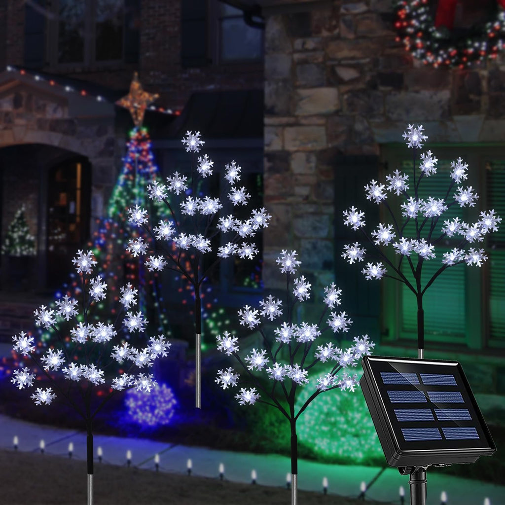 Outdoor snowflake stake lights with solar panel in front of a decorated house at night