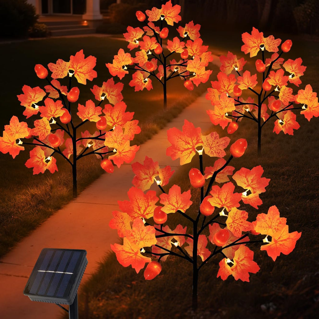 Four illuminated solar maple leaf and acorn yard stake lights on a pathway at dusk