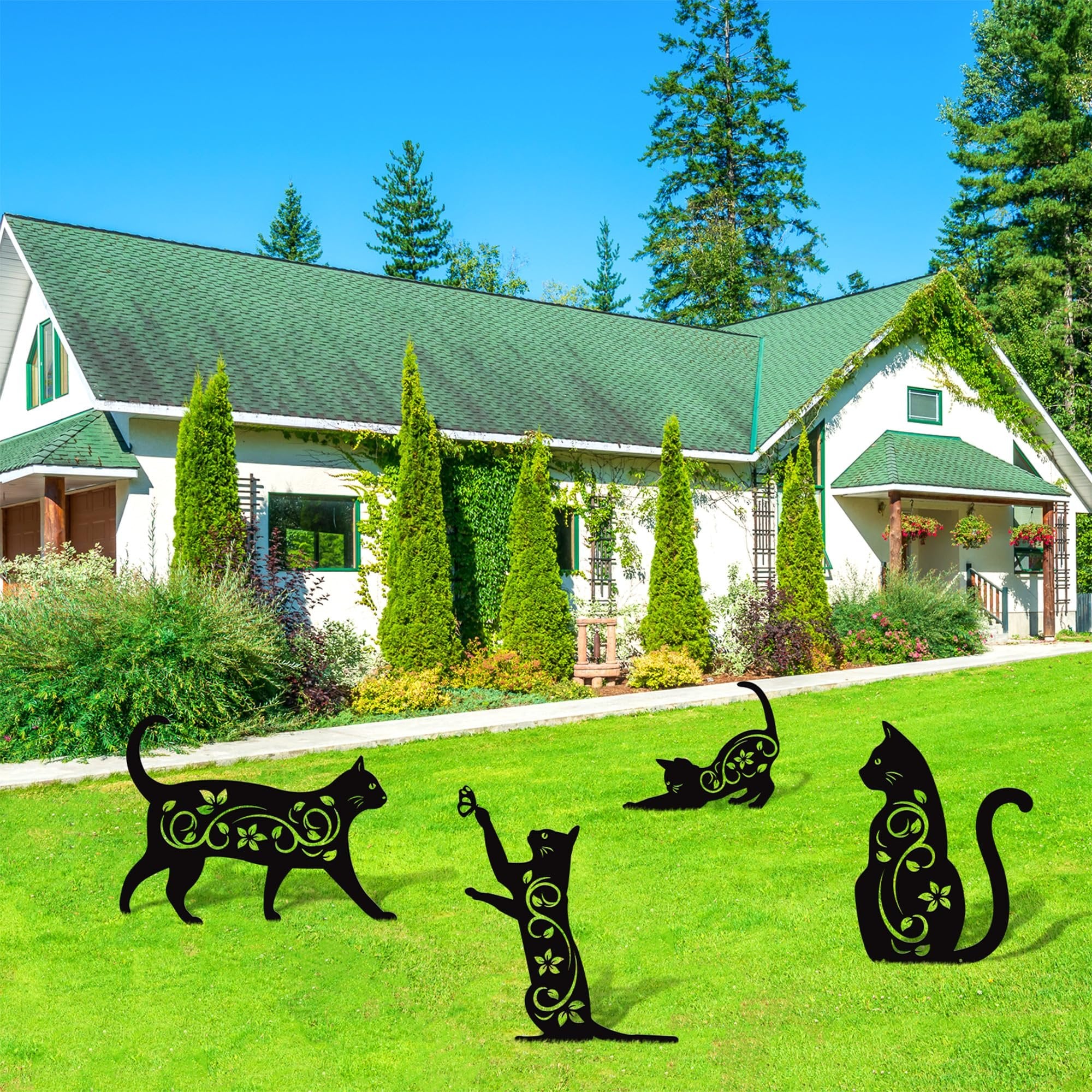 Four black metal cat silhouette garden stakes with floral cutouts on a green lawn in front of a house.