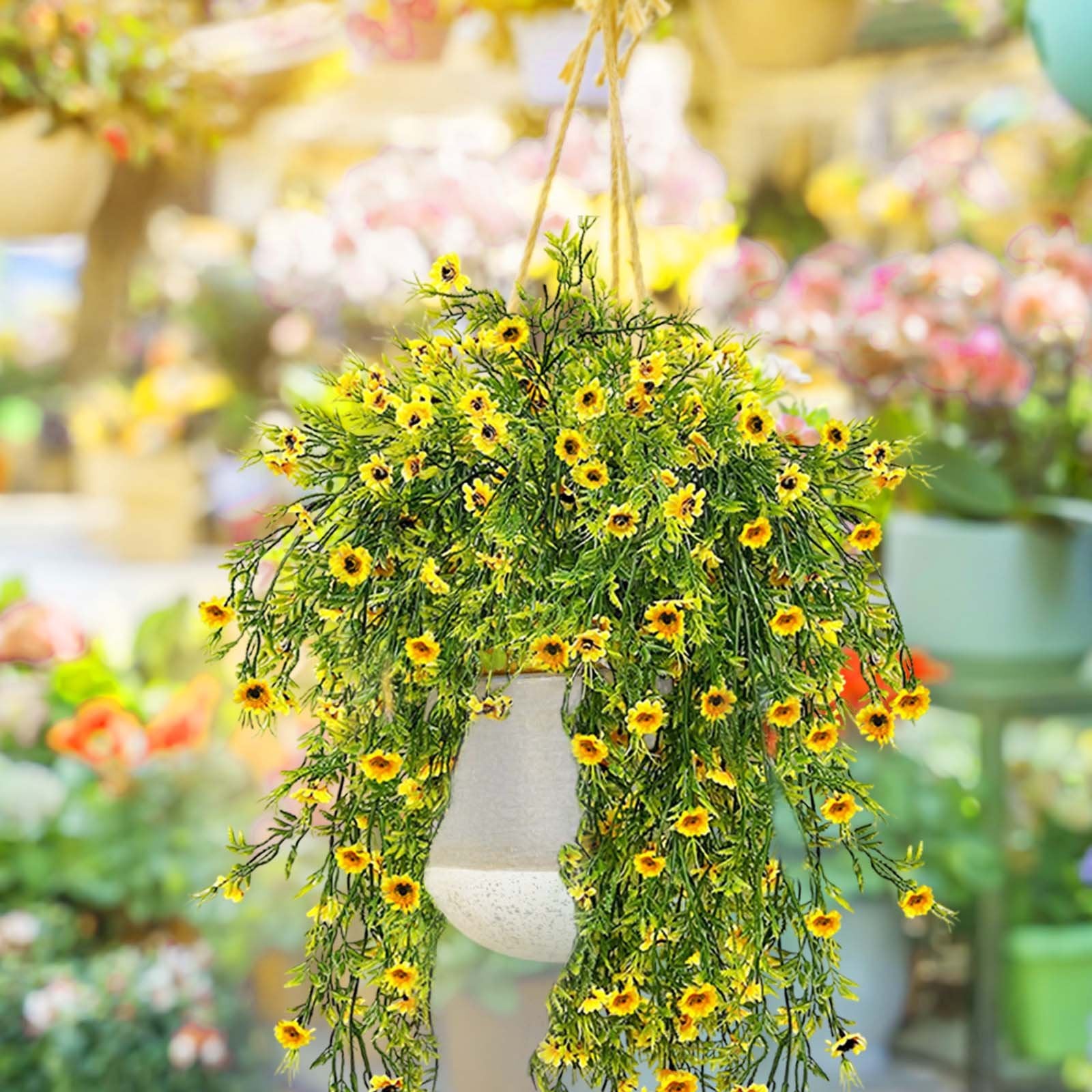 Hanging artificial daisy plant with bright yellow flowers and green foliage in a textured pot, suspended by rope.