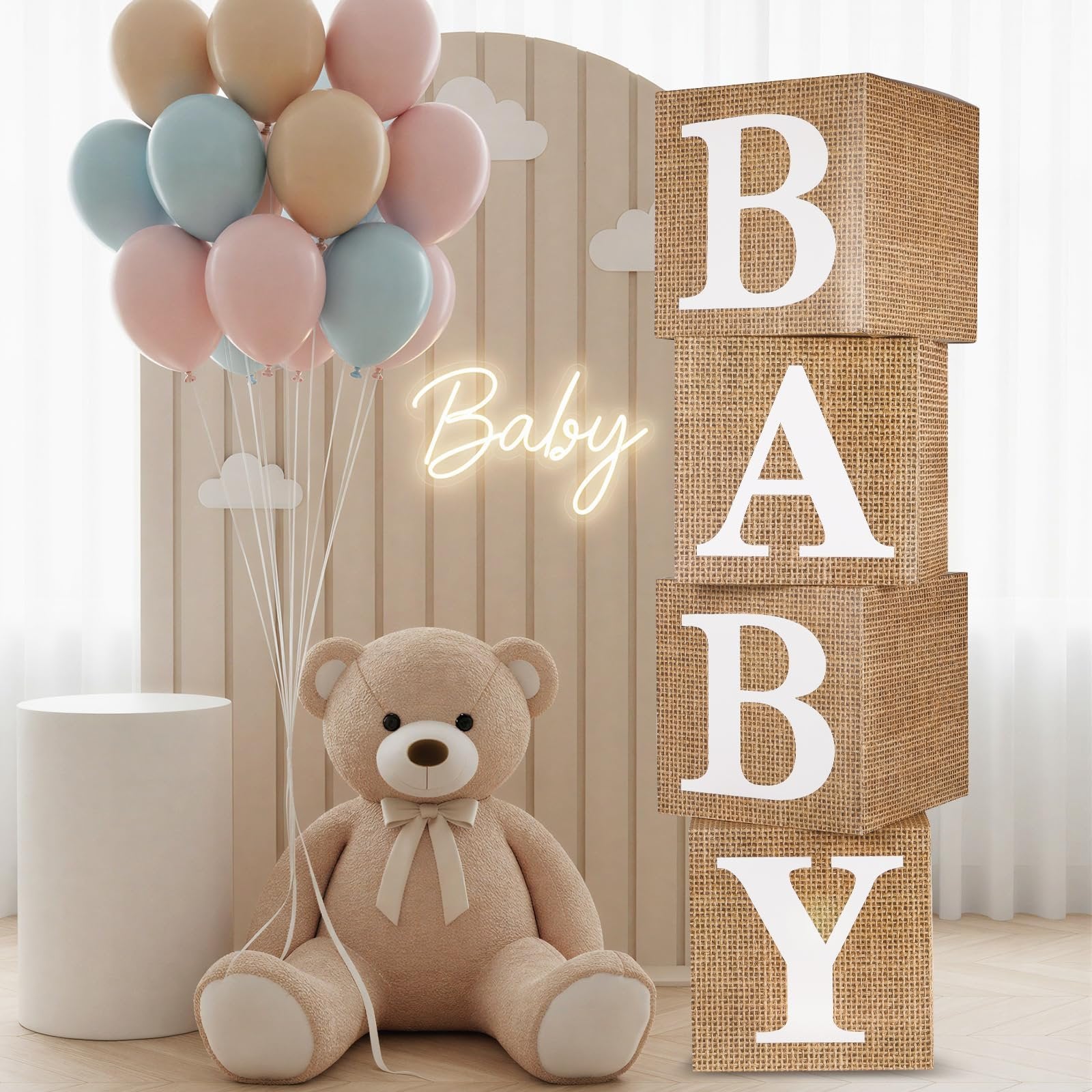 Four burlap baby blocks spelling BABY, a teddy bear, and pastel balloons for a baby shower decoration setup.