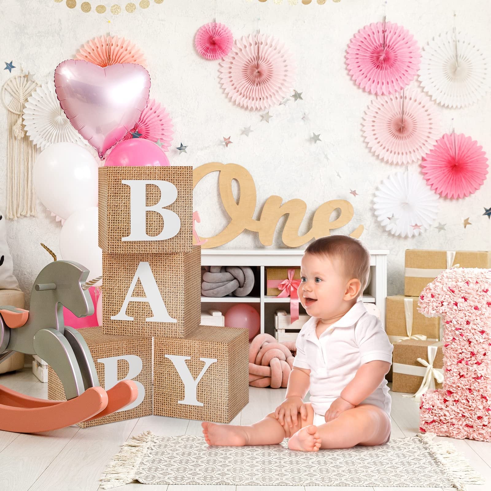 Baby sitting near burlap blocks spelling BABY and a large number 1 decoration, surrounded by party decor.
