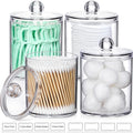 Four clear acrylic bathroom canisters filled with cotton swabs, cotton balls, cotton pads, and floss picks.
