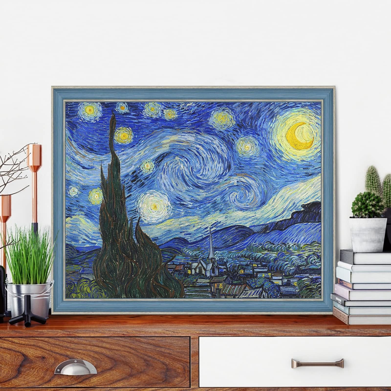 Diamond painting kit of Van Gogh's Starry Night, framed and displayed on a wooden dresser with plants and books.