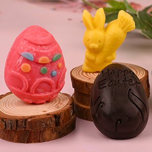 Easter chocolate molds in the shape of a decorated egg, a bunny with a carrot, and an egg with 'Happy Easter' text.