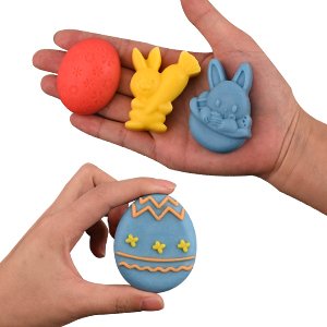 Hands holding Easter-themed silicone molds in bunny and egg shapes, one mold is decorated with zigzags.